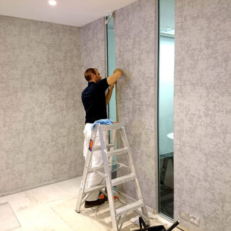 Expert installing vibrant wallpaper on a wall, ensuring a smooth finish