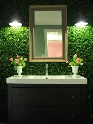 Vanity with mirror and vases of flowers against foliage backdrop