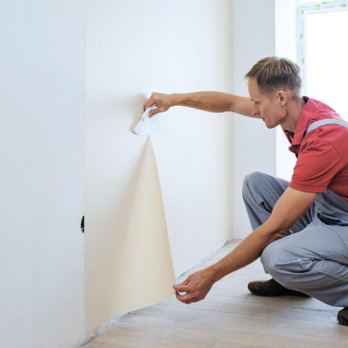 Close-up of hands applying wallpaper to a wall